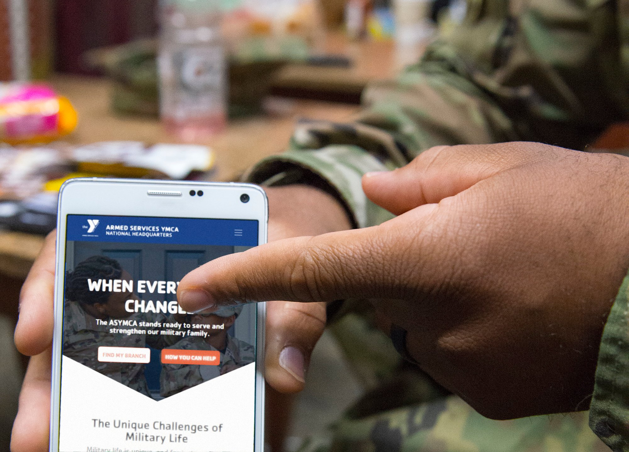 Service member scrolls the ASYMCA website on their smart phone